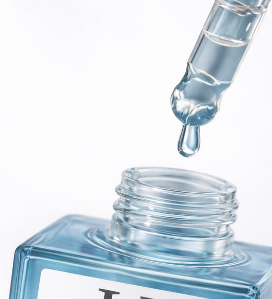 Clear dropper bottle with a droplet of liquid on a white background