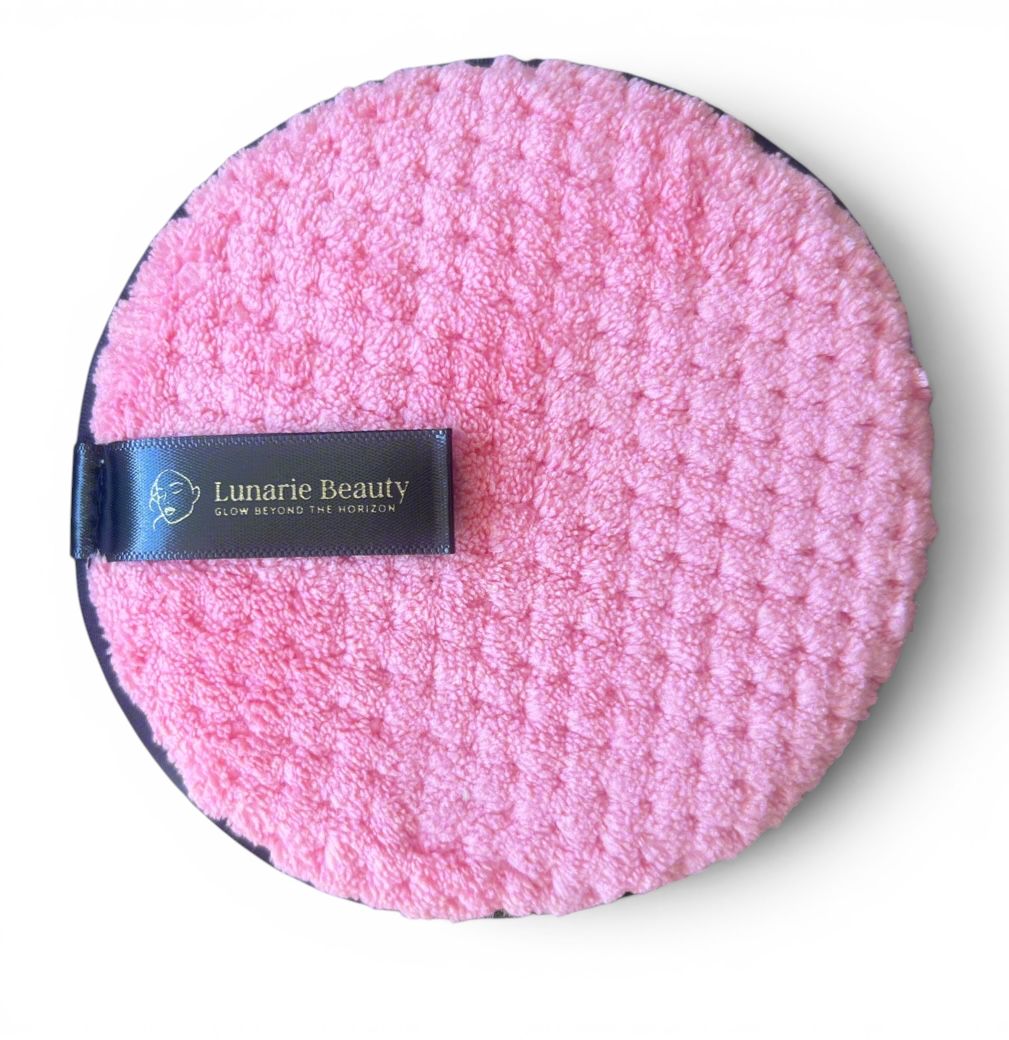 Pink round cleaning pad with a blue band featuring 'Lumarie Beauty' on a gray background