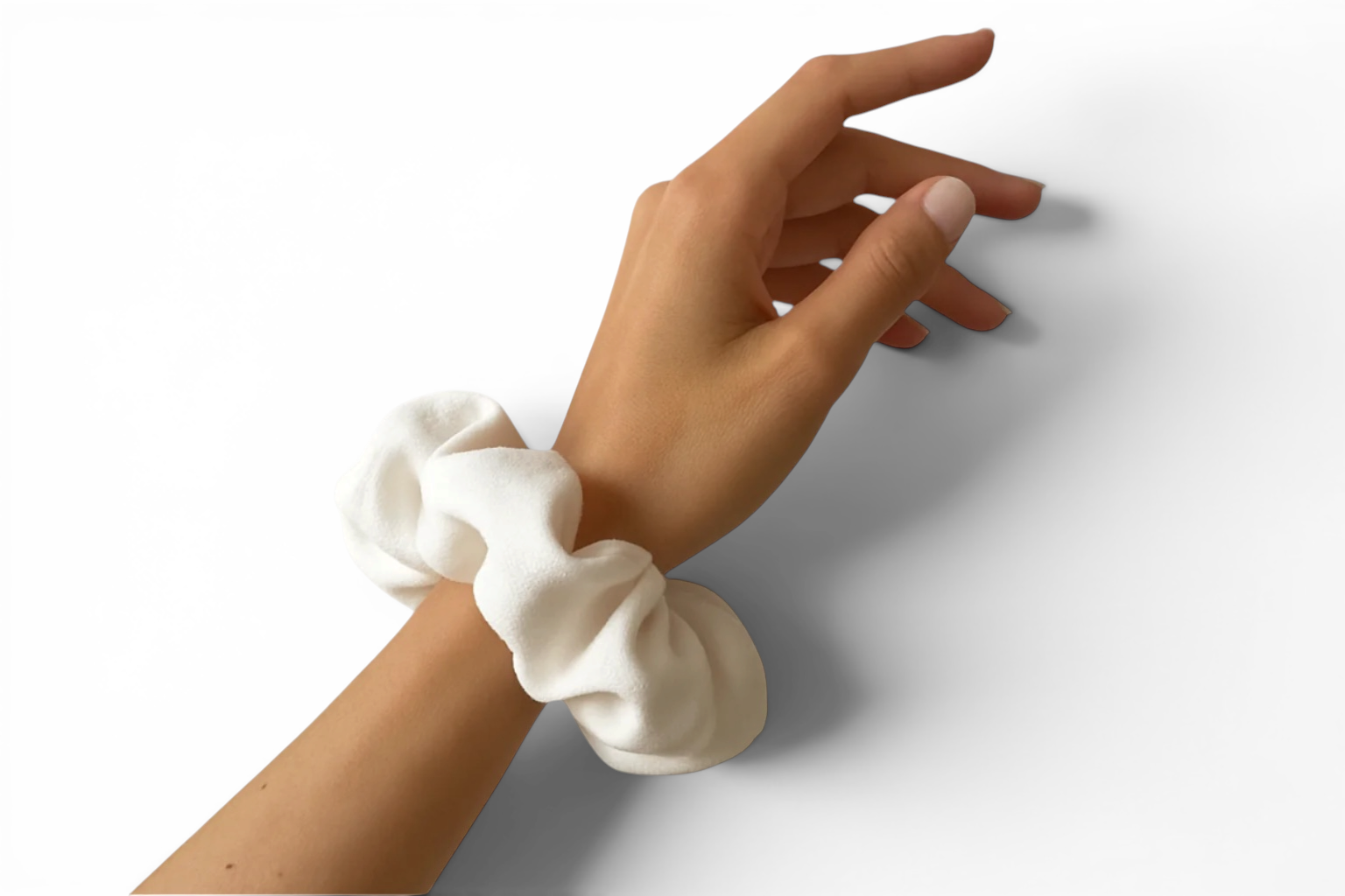 White scrunchie on a wrist with a neutral background